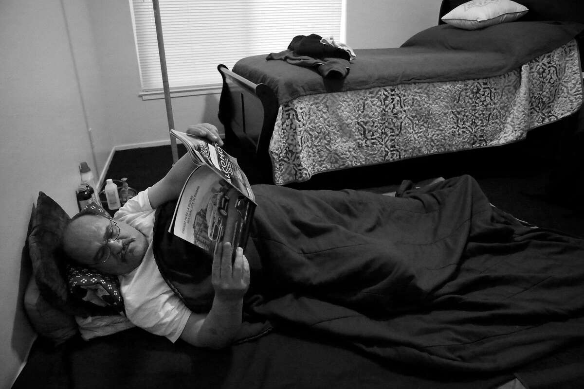 Luis Castellano reads as he lays on the floor in his bedroom next to the new bed in his apartment on Monday, May 22, 2017 in San Francisco, Calif. Castellano says he is still lays down the bed clothes he used while camping in Golden Gate Park to sleep on his floor in his new apartment.