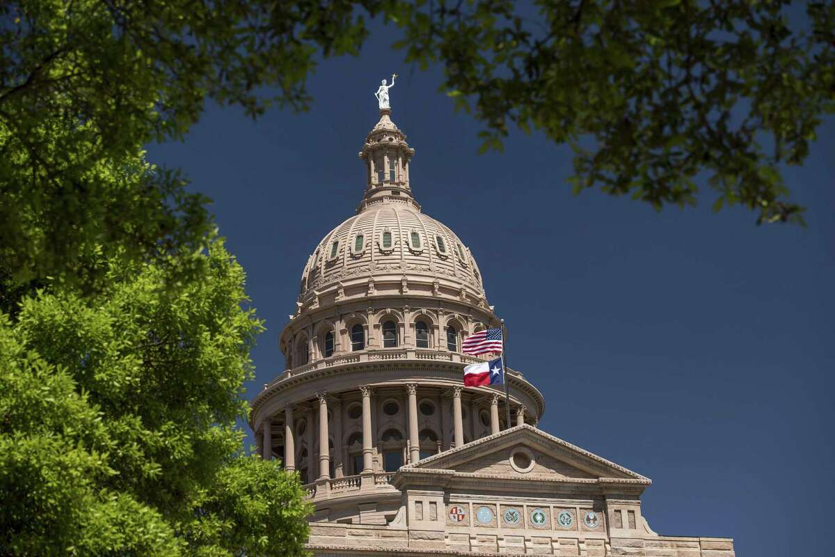 An American flag flies with the Texas state flag outside the Texas State Capitol building in Austin.