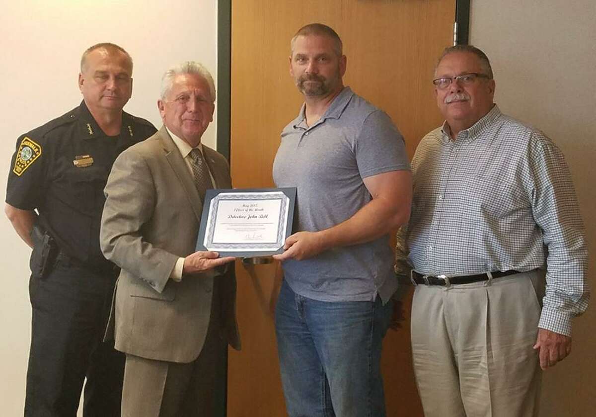 Detective John Bell, center, receives the May Officer of the Month award from Mayor Harry Rilling. Also pictured are Norwalk Police Chief Thomas Kulhawik (left) and police commissioner Charles Yost.