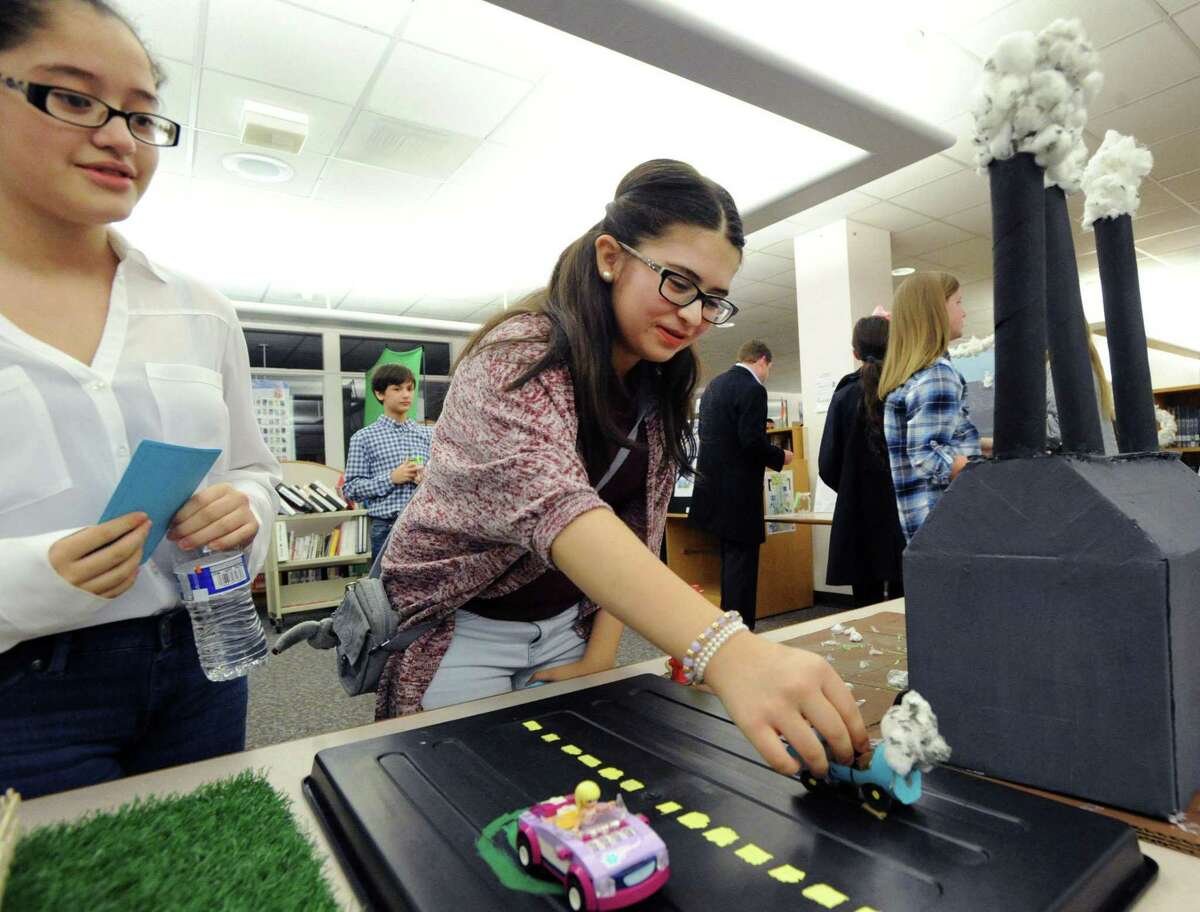 Western Middle School 7th graders Diana Tello, 12, left, and Ali Fuentes, 13, demonstrate their climate change project showing what the world will look like if nothing is done about climate change during opening night for the Climate Change Museum produced by the 7th Grade STEMinar class at Western Middle School. The program has finished its first pilot year.