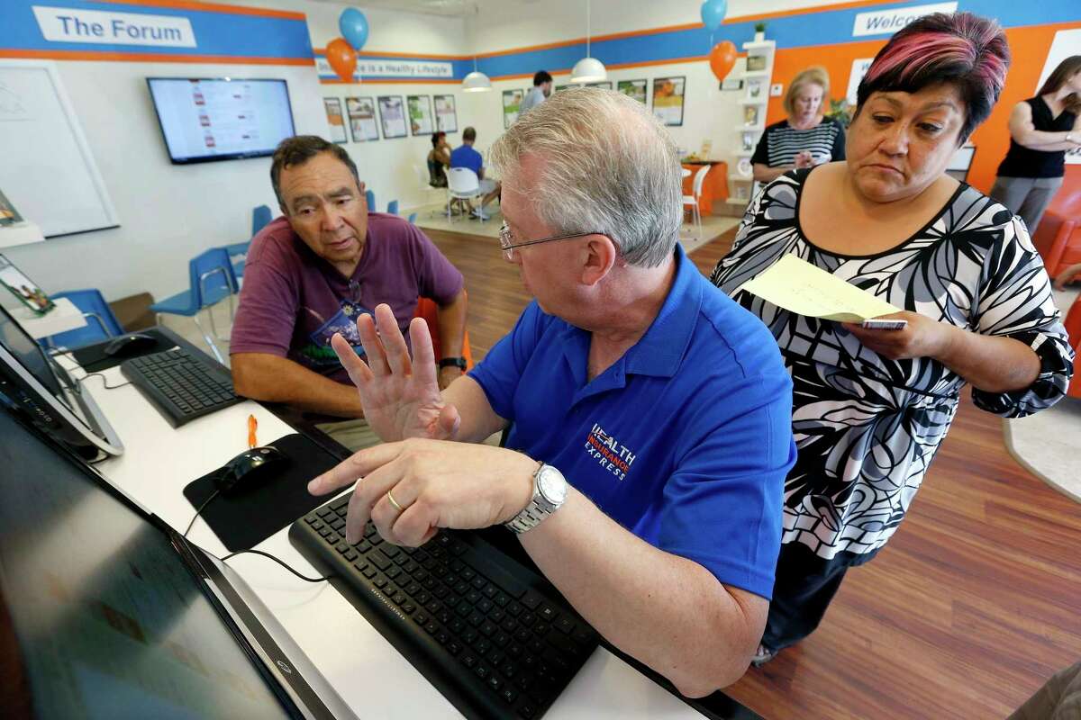 FILE - In this Tuesday, Oct. 1, 2013, file photo, Alan Leafman, center, president of Health Insurance Express, Inc., helps Raquel Bernal, right, and her husband John Bernal, both of Apache Junction, Ariz., navigate the nation's health care insurance system online at the Health Insurance Express store in Mesa, Ariz. (AP Photo/Ross D. Franklin, File)