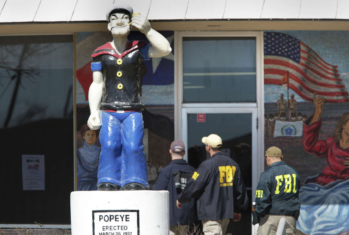 FBI agents walk into Crystal City City Hall past a statue of Popeye, the city's mascot, seizing computers and documents and arresting city officials in 2016. The city's mayor and city manager are now on trial.
