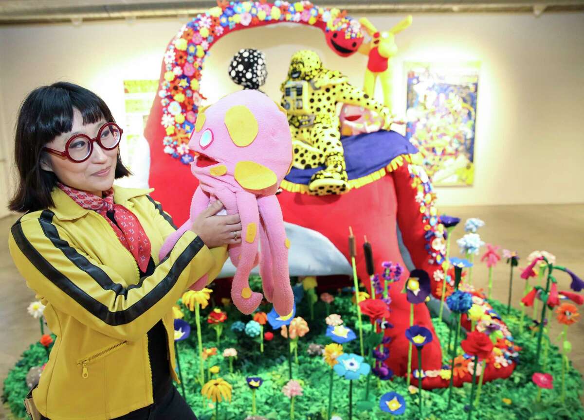 Artist Joo Young Choi poses for a portrait with Putt-Putt, a character from a world that she created, next to her "Time for You and Joy to Get Acquainted."