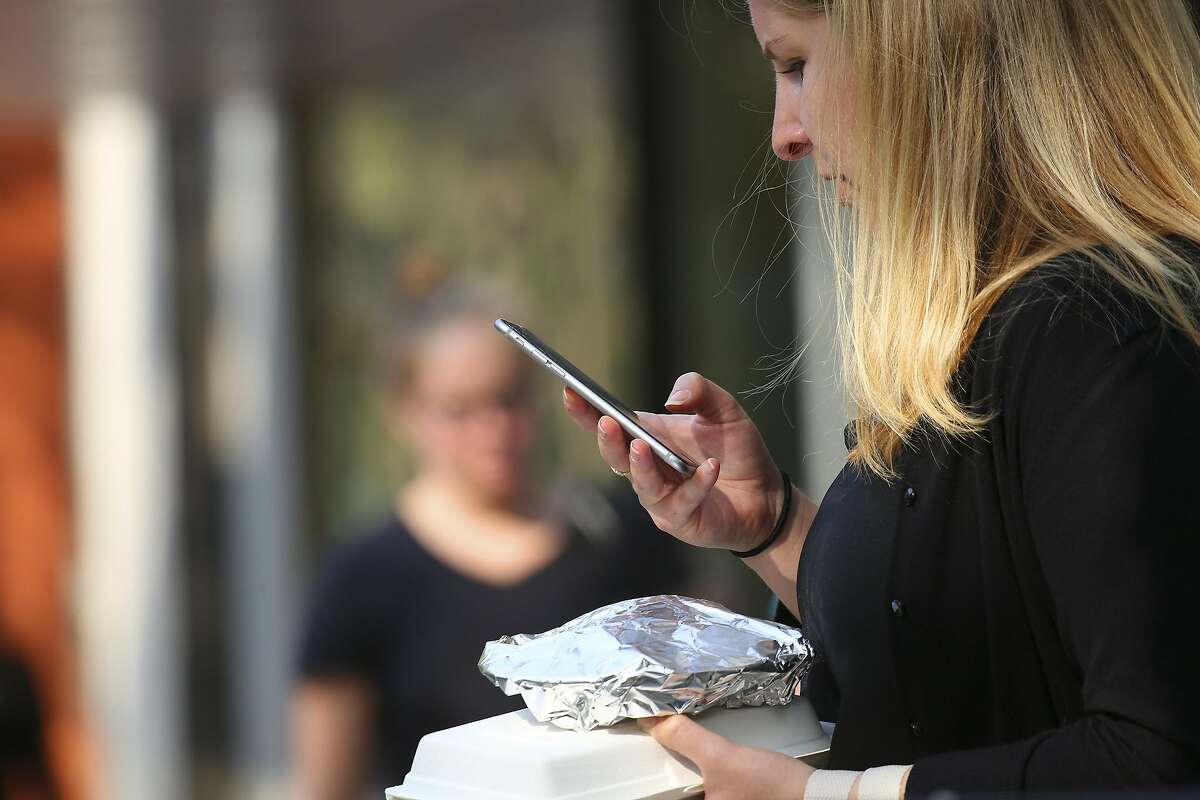 FILE – A woman checks her mobile device while walking on University Avenue in Palo Alto, Calif., on Sept. 19, 2016. A former Senate candidate from California reportedly left voicemails detailing his plans to establish a "regional capital" in North Idaho. 
