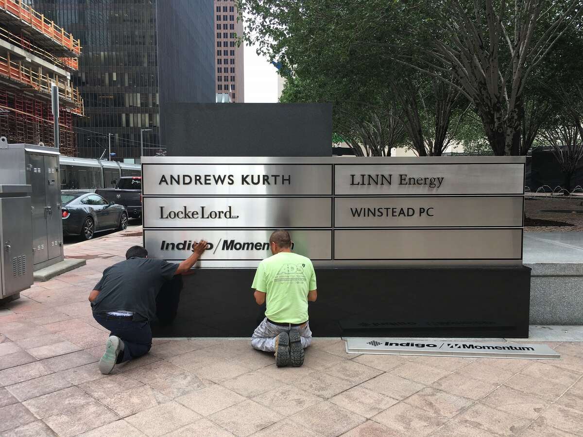 Workers install signage for Indigo/Momentum outside JPMorgan Chase Tower in downtown Houston Thursday, June 22, 2017.