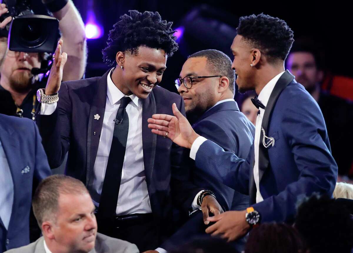 Kentucky's De'Aaron Fox, center in top photo, is all smiles as he heads to the stage to be introduced after being selected fifth overall by the Sacramento Kings in the NBA draft Thursday night.