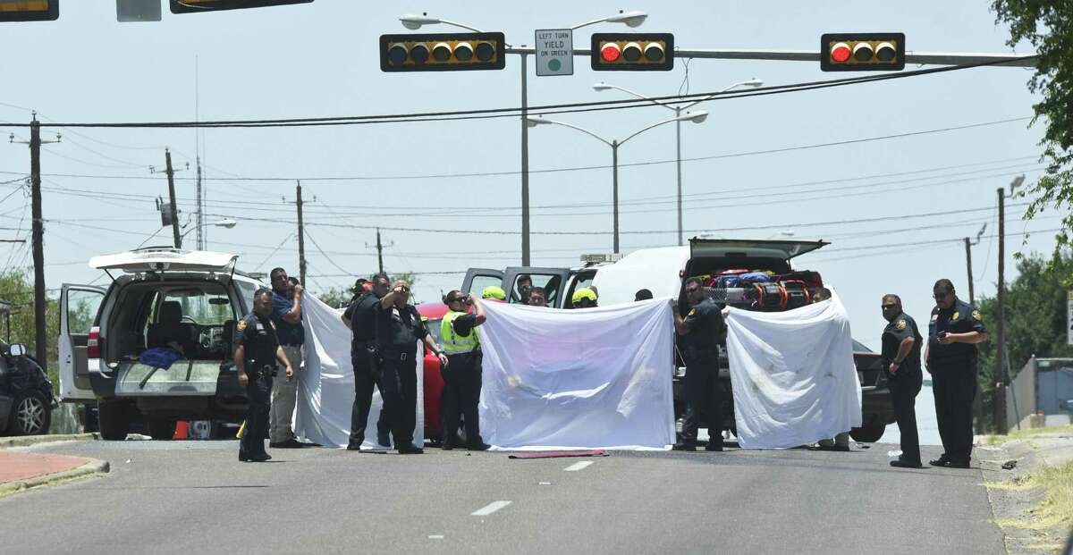 Laredo Police officers hold up sheets to conceal the body of a victim involved in a multi-car collision at the intersection of Clark Boulevard and Cedar Avenue on Thursday, June 22, 2017.