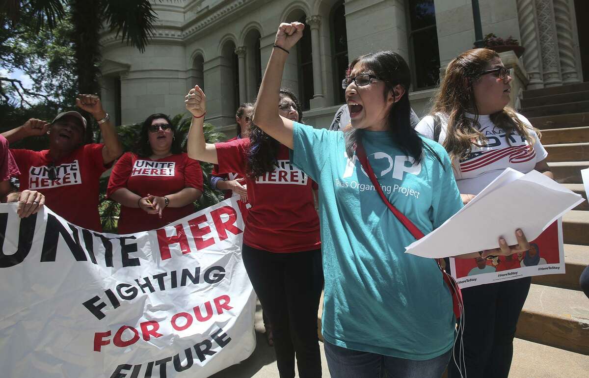 Jessica Azua (right, foreground, arm raised) leads a chant Thursday June 1, 2017 during an announcement made in front of city hall regarding a lawsuit over Senate Bill 4. Senate Bill 4 allows police officers to question a person?’s immigration status during a detainment.
