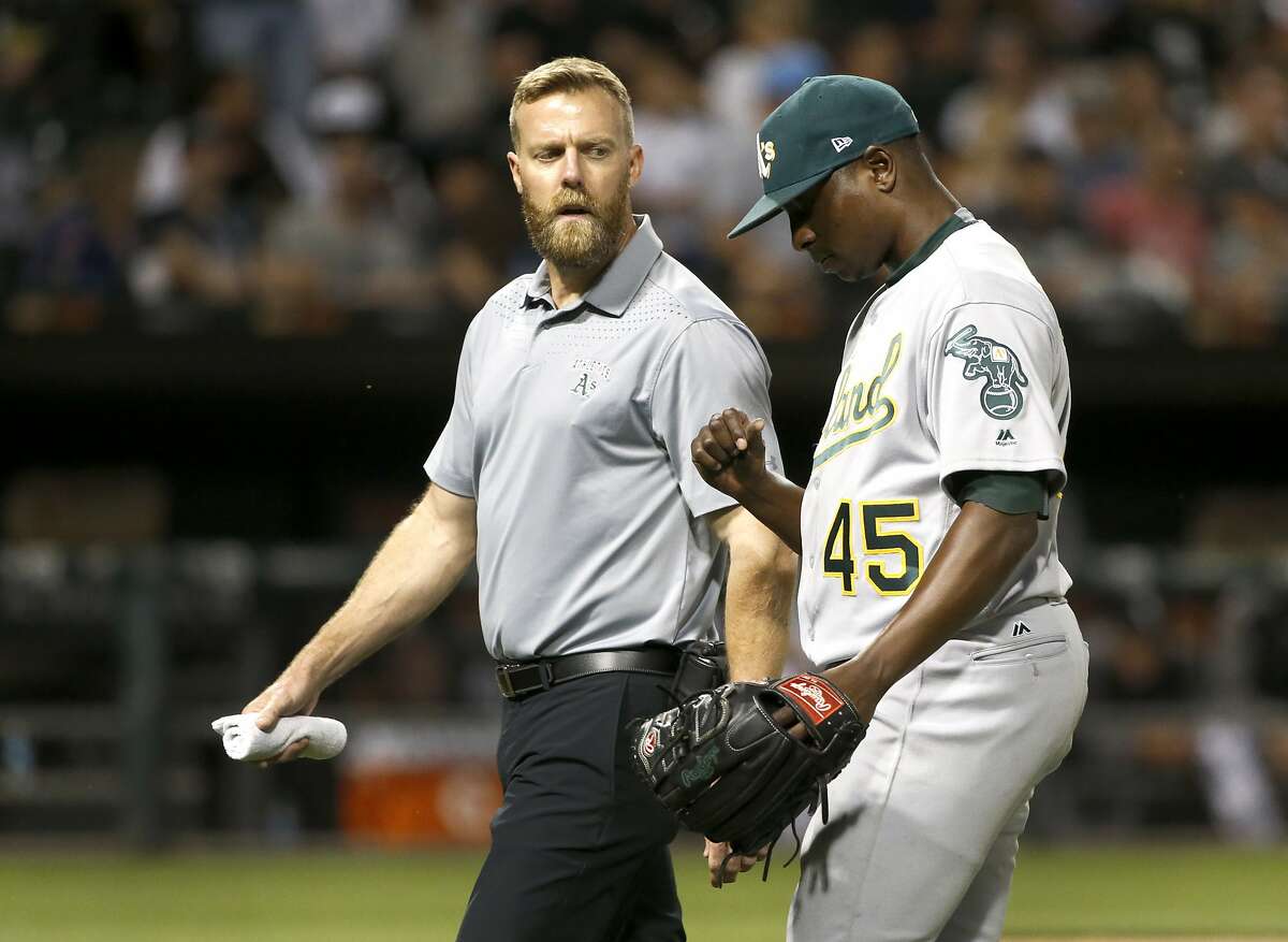 Oakland Athletics starter Jharel Cotton, right, leaves the game looking at his pitching thumb with a member of the medical staff during the sixth inning of a baseball game against the Chicago White Sox, Friday, June 23, 2017, in Chicago. (AP Photo/Charles Rex Arbogast)