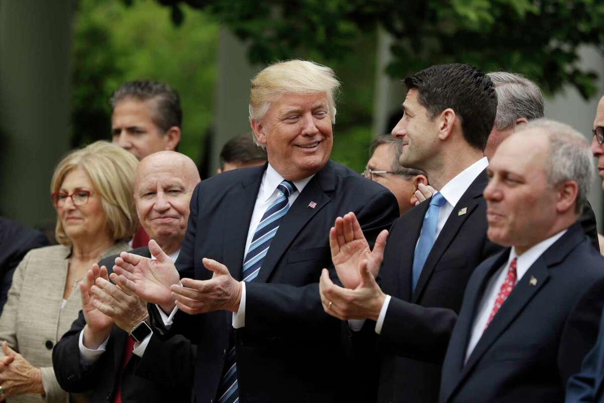 President Donald Trump, flanked by House Ways and Means Committee Chairman Rep. Kevin Brady, R-Texas, and House Speaker Paul Ryan of Wis. applaud in the Rose Garden of the White House in Washington, Thursday, May 4, 2017, after the House pushed through a health care bill. (AP Photo/Evan Vucci)