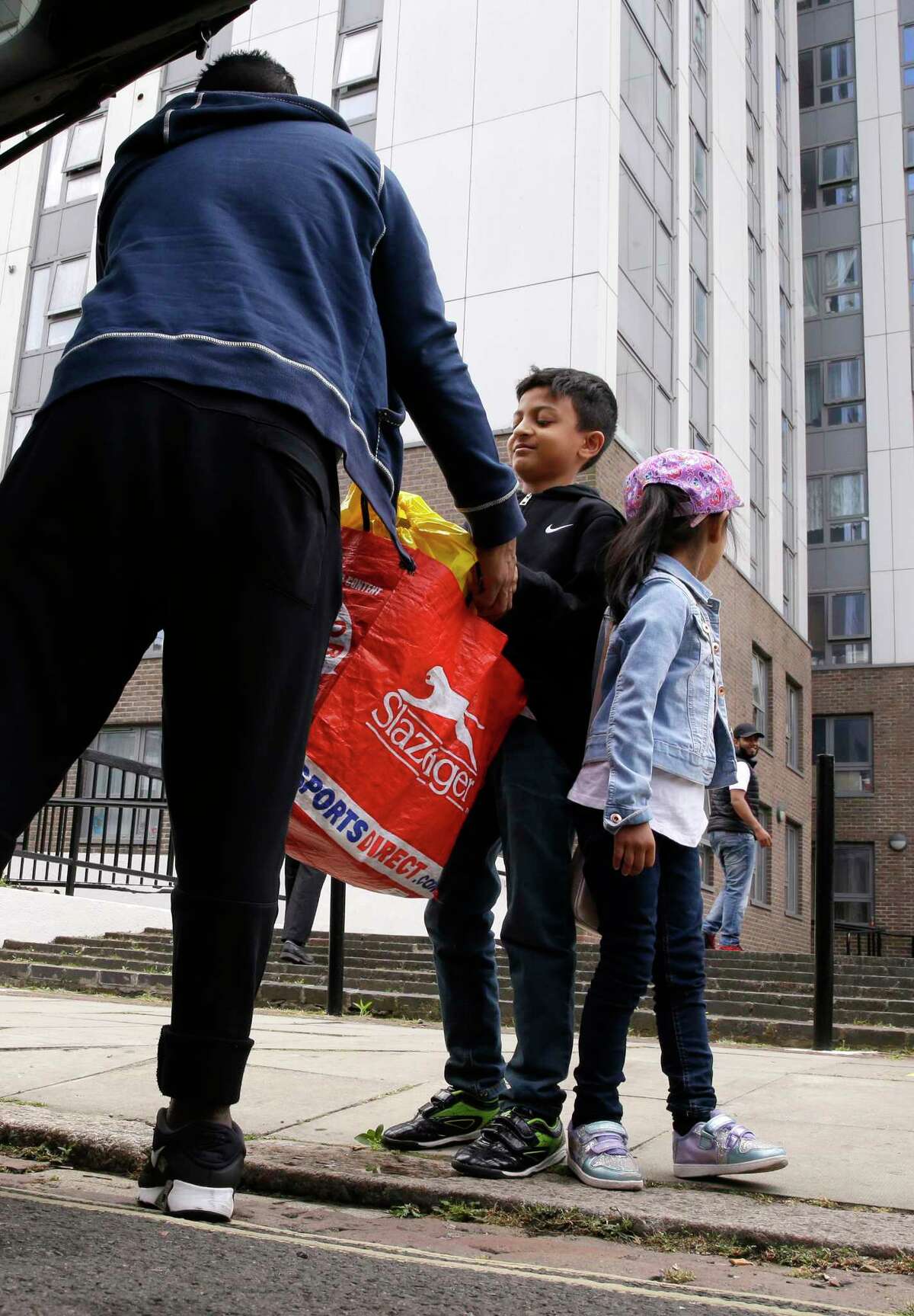 A young boy helps with their belongings as they voluntarily evacuate Dorney block, part of the Chalcots Estate in the borough of Camden, north London, Saturday June 24, 2017, after the local council evacuated some 650 homes overnight. Camden Borough Council said in a statement Saturday that it housed many of the residents at two temporary shelters while many others were provided hotel rooms, after inspectors found fire safety issues in housing towers, following the inferno in a west London apartment block that killed 79. (AP Photo/Alastair Grant) ORG XMIT: LON104