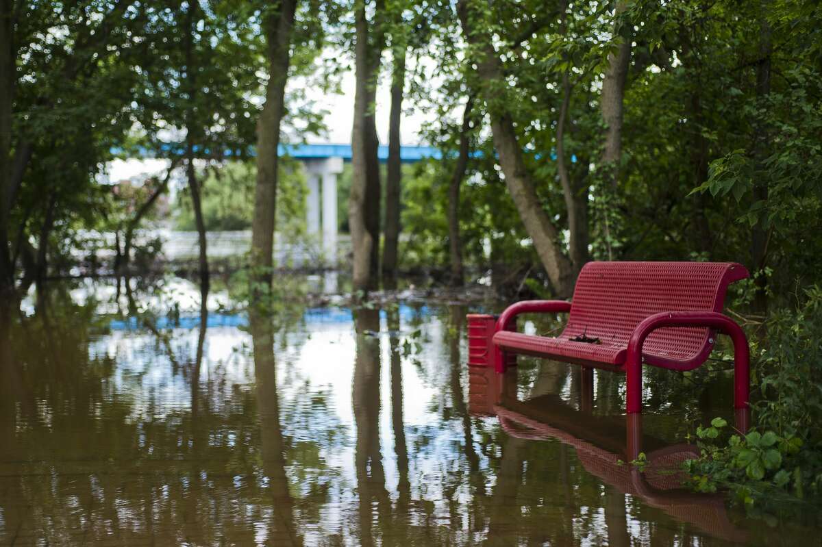 Floodwater surrounds a park bench behind Riverside Place Senior Living Community on Sunday, June 25, 2017.