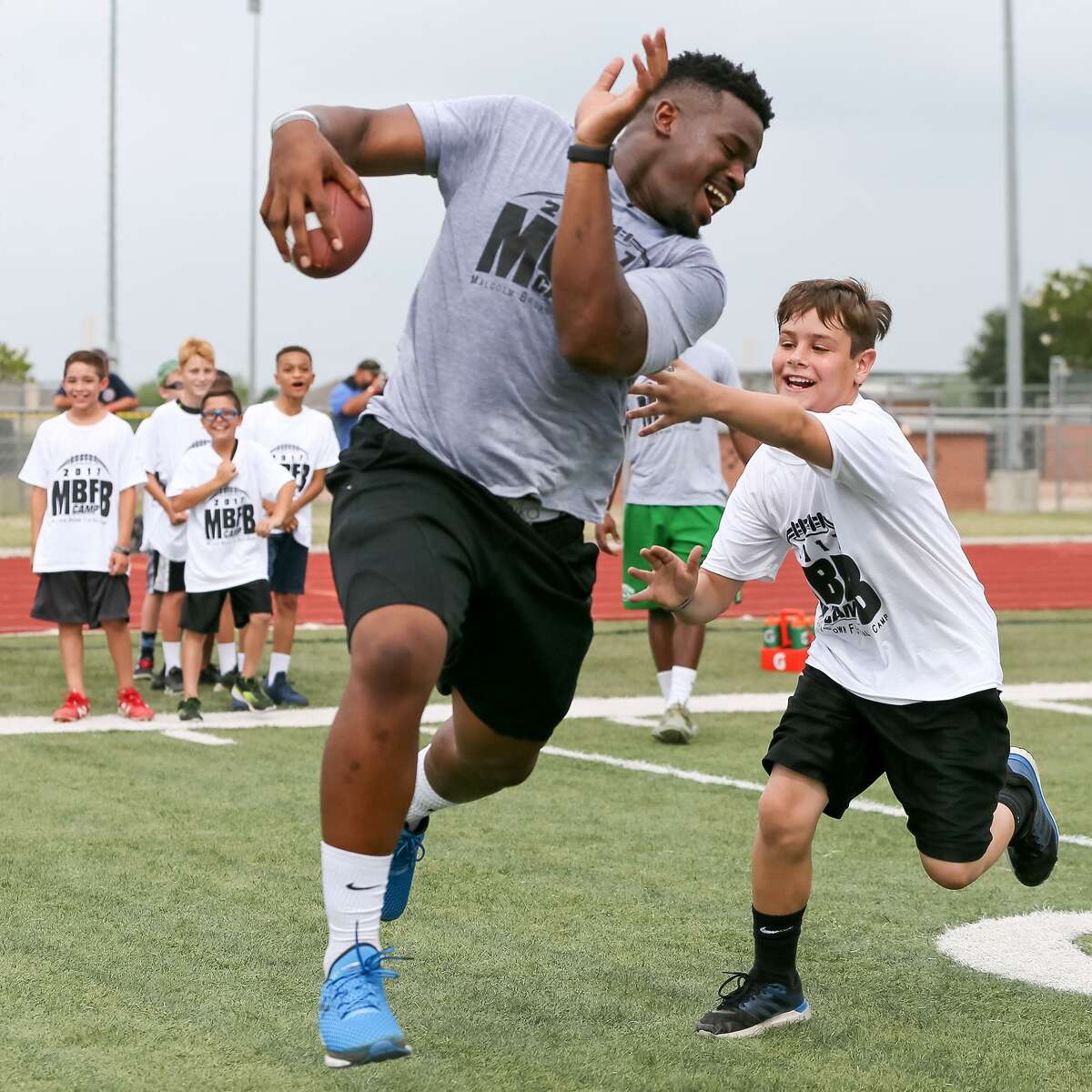 Tyler Drake, 10, tries to catch Malcolm Brown in a running back drill at the Malcom Brown Youth Football Camp where the Los Angeles Rams' running back and other NFL and college players taught leadership and football skills to kids ages 6-13 at Steele High School on Saturday, June 24, 2017.
