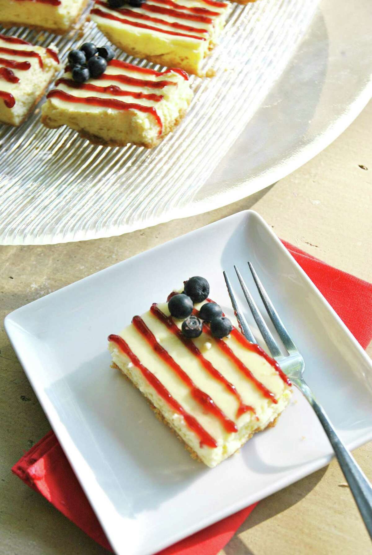 American Flag Cheesecake Bars use raspberry-jam piping for the stripes and blueberries for the stars.