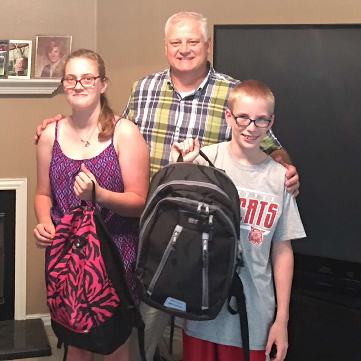 Lion Scott Perry, center, delivers backpacks full of goodies from the Conroe Noon Lions Club, to Amber, left, and Carson Free as they head off for a week long camping session at Texas Lions Camp in Kerrville, Texas.