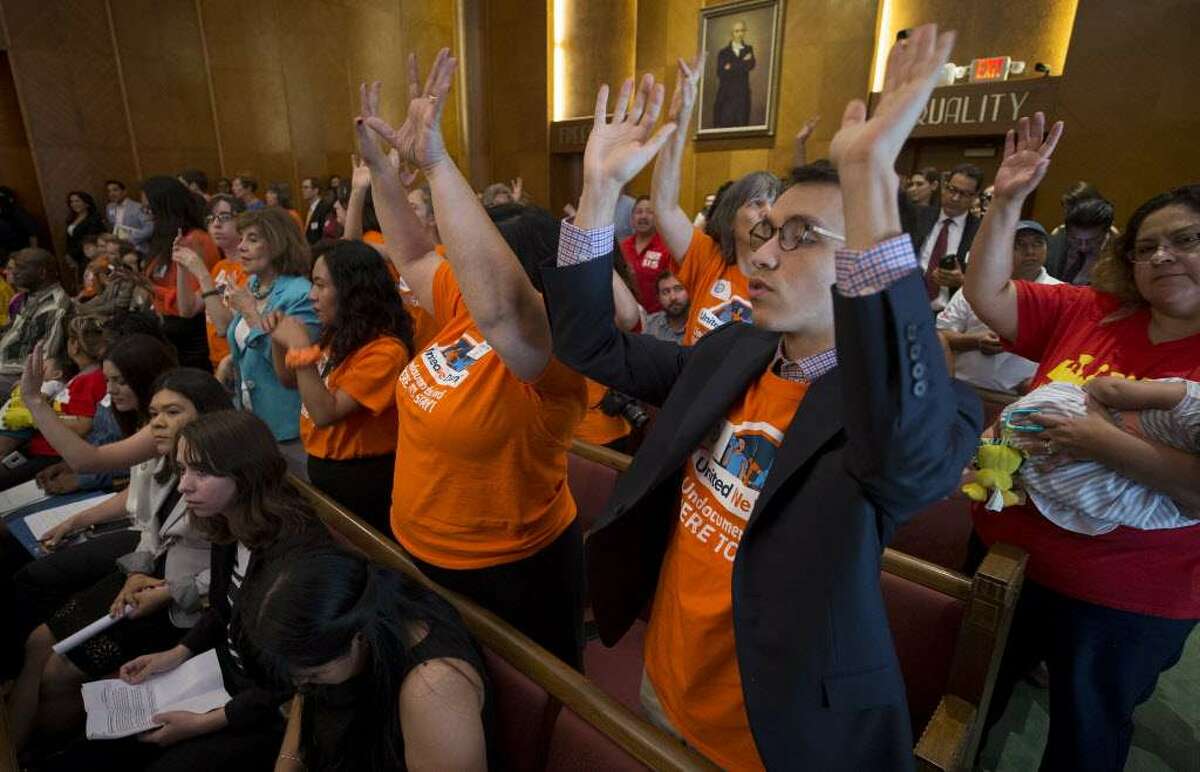 People raise their hands in support of state Sen. Sylvia Garcia's comments at a Houston City Council meeting in favor ofthe city joining a lawsuit challenging Senate Bill 4.