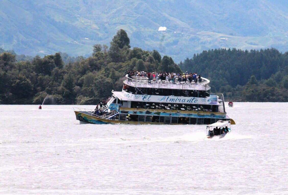 A boat races towards the sinking El Almirante ferry at a reservoir in Guatape, Colombia, Sunday, June 25, 2017. Scuba divers on Monday continued searching for bodies in the reservoir near the Colombian city of Medellin where a tourist boat packed with passengers for the holiday weekend sunk, leaving at least six people dead and 15 missing. (Photo by Juan Quiroz via AP)