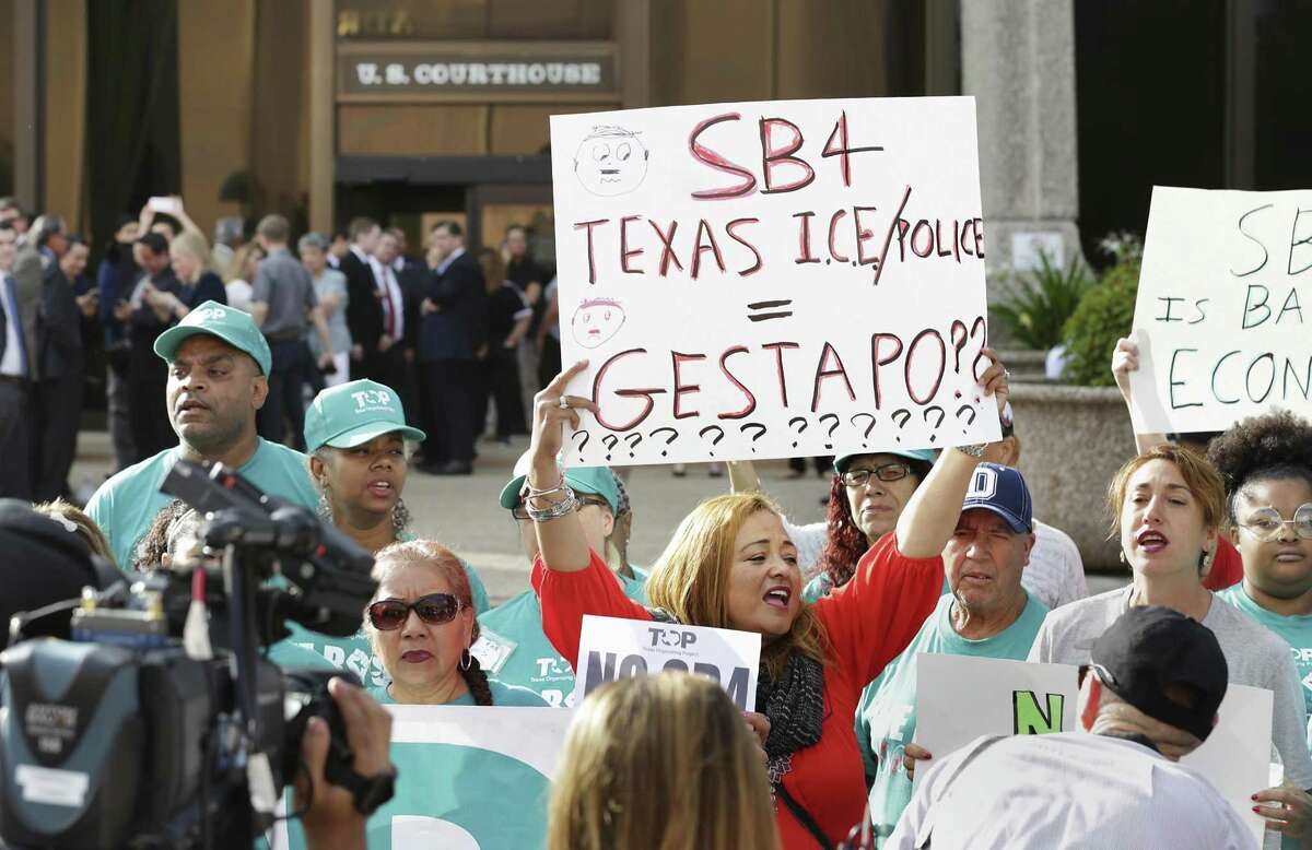 Marilu Frutuoso, center in red, of Oaxaca, Mexico, holds a sign with other protestors during a rally in front of the federal courthouse in San Antonio against SB 4 on June 26, 2017.