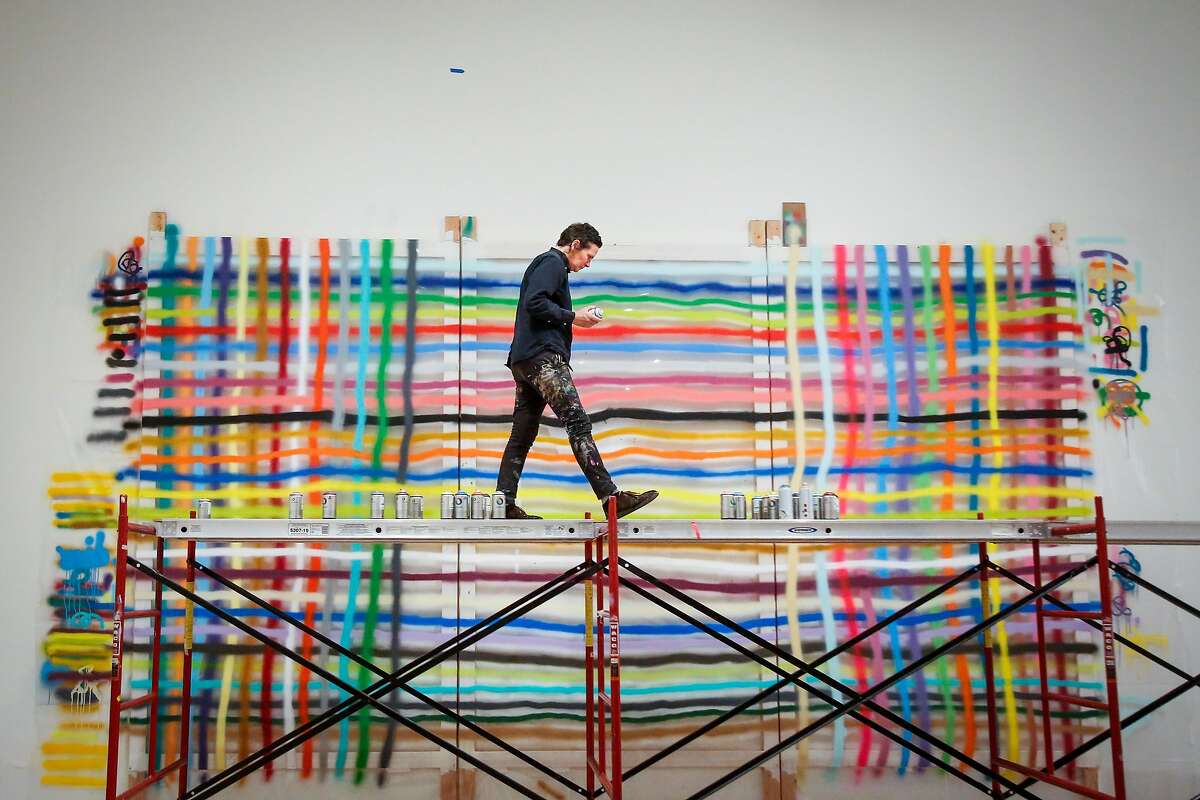 Alicia McCarthy works on her exhibit, a large piece on plexiglas, in the San Francisco Museum of Modern Art in San Francisco on Friday, June 23, 2017.