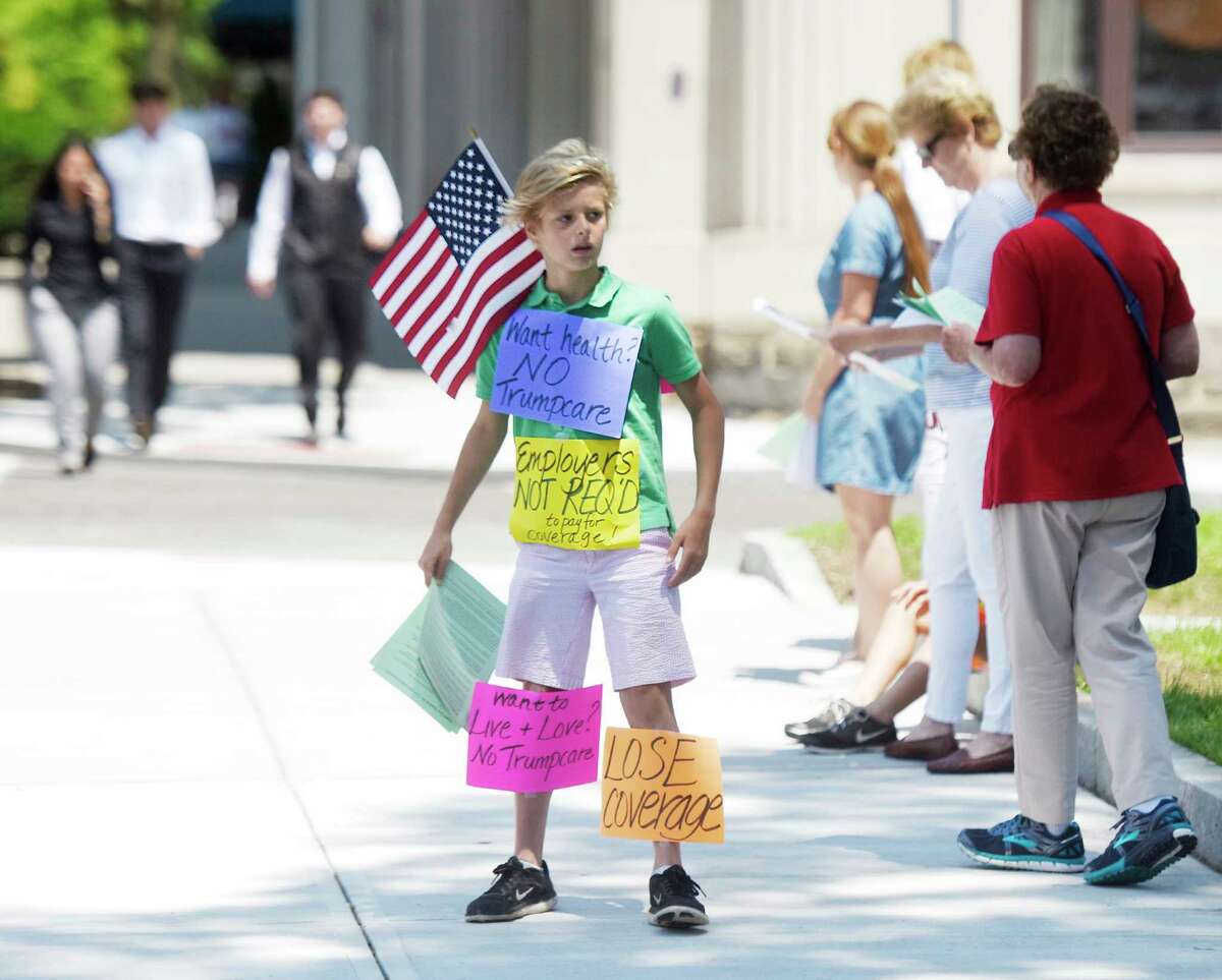 Riverside's Tyler Fahey, 11, shows an array of signs during the anti-Trump group Indivisible Greenwich's protest against the new proposed American Health Care Act outside the Senior Center in downtown Greenwich, Conn. Tuesday, June 27, 2017. The group gave fact sheets about the new proposed healthcare and urged passersby to call their Senators. Facing opposition from both parties, Senate Majority Leader Mitch McConnell announced Tuesday he would delay consideration of the bill until after the Senate's weeklong July 4 recess.