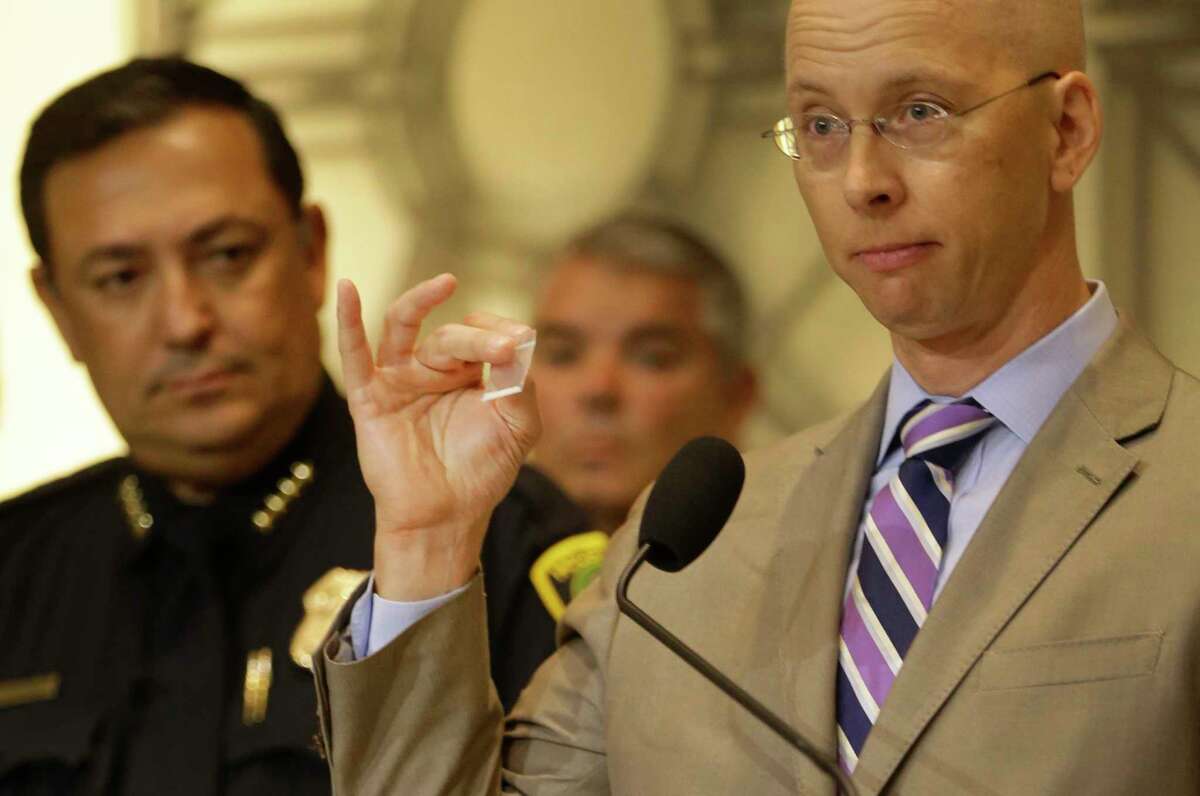 Houston Police Dept. Chief Art Acevedo, left, listens as Dr. Peter Stout, right, Houston Forensic Science Center CEO and president, speaks during a media conference to discuss the seizure of a highly potent synthetic opioid in Houston held at City Hall Tuesday, June 27, 2017, in Houston. He is holding a small bag of sugar to demostrate the amount of 80 milligrams of carfentanil that was seized. That amount could kill 4,000 people.