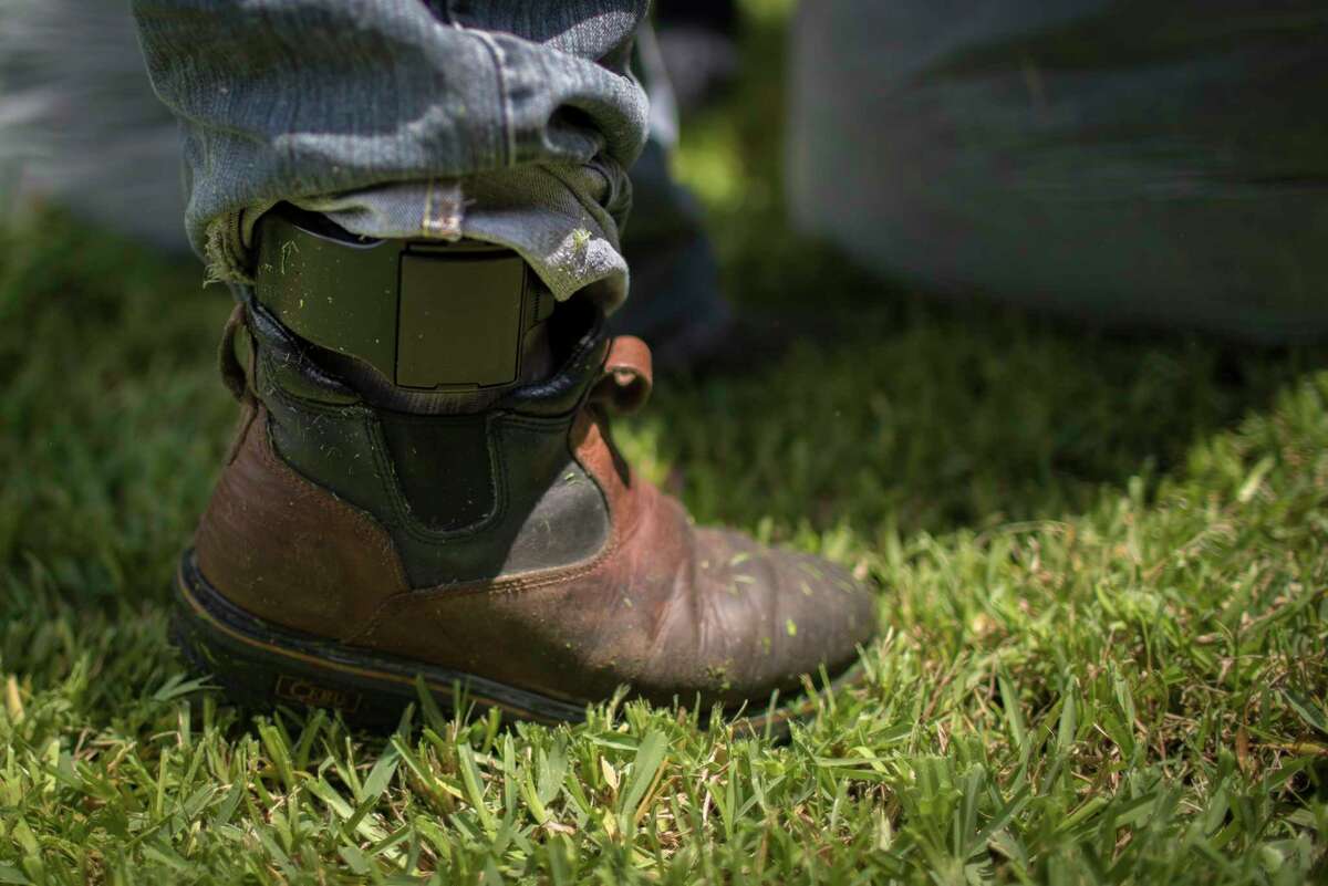 Juan Rodriguez, 47, takes a break from mowing the lawn of his home, Tuesday, June 27, 2017, in Houston, wearing a bracelet ankle monitoring tracker.