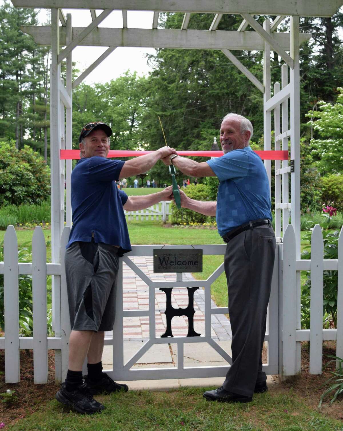 Lee Colville, a member of the Harrybrooke board of managers, right, and his son, Steve, who laid the bricks of a new memorial walkway in the garden at the park with Pete Messer, cut the ribbon at the walkway’s recent dedication ceremony.