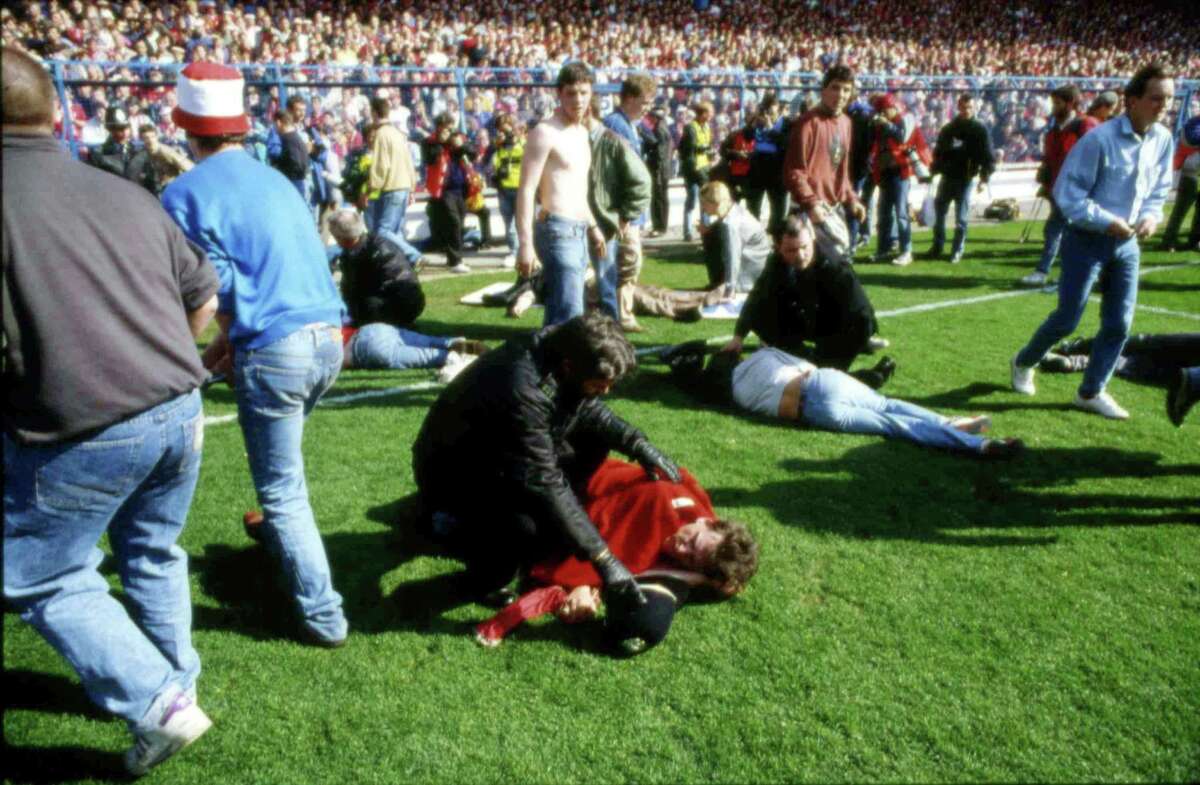 FILE - In this April 15, 1989 file photo, police, stewards and supporters tend and care for wounded supporters on the pitch at Hillsborough Stadium, in Sheffield, England. British prosecutors on Wednesday June 28, 2017, are set to announce whether they plan to lay charges in the deaths of 96 people in the Hillsborough stadium crush _ one of BritainÂ?’s worst-ever sporting disasters. (AP Photo, File)