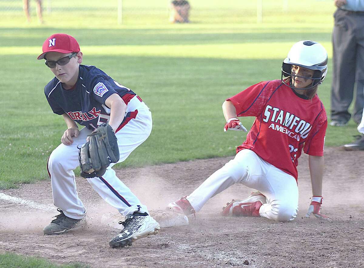 Norwalk third baseman Seamus Herlihy, left, spears the ball out of the air as Stamford American's Charlie Karukas slides safely into third in a District 1 Little League pool play game at Broad River Field in Norwalk. Stamford American won 5-4 in seven innings.