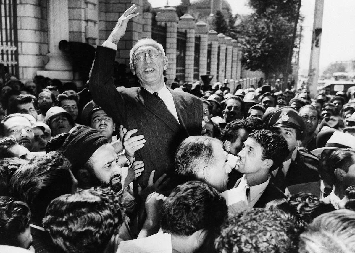 FILE- In this Sept. 27, 1951 file photo, Prime Minister Mohammed Mosaddegh rides on the shoulders of cheering crowds in Tehran's Majlis Square, outside the parliament building, after reiterating his oil nationalisation views to his supporters. Once expunged from its official history, documents outlining the U.S.-backed 1953 coup in Iran have been quietly published in June 2017, by the State Department, offering a new glimpse at an operation that ultimately pushed the country toward its 1979 Islamic Revolution and hostility with the West. (AP Photo, File)