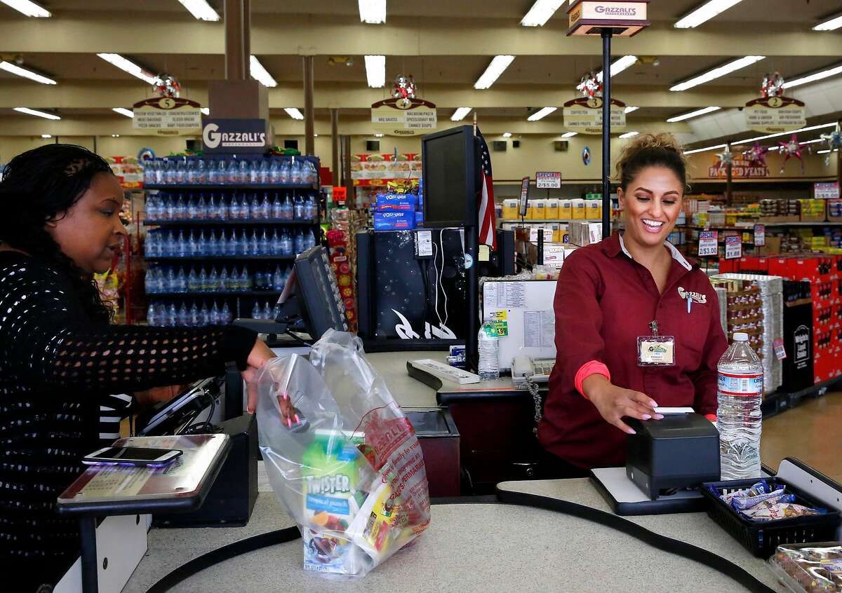 Faye Algazzali, an owner, right, rings up the purchases of Jonell Walker, left, at Gazzali's Supermarket June 28, 2017 in Oakland, Calif.