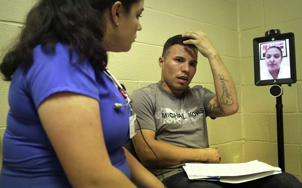 Abraham Gomez, center, tells student nurse Stephenie Decker, left, about an injury to his head that has caused him to have frequent headaches, at a health clinic in the El Cenizo Community Center in El Cenizo, Tx, on Tuesday, June 27, 2017. The U.S. Army and students from the Texas A&M medical system have been working together on a large-scale health care training exercise in small communities around Laredo, TX. At left is an off-site interpreter to help with translations.