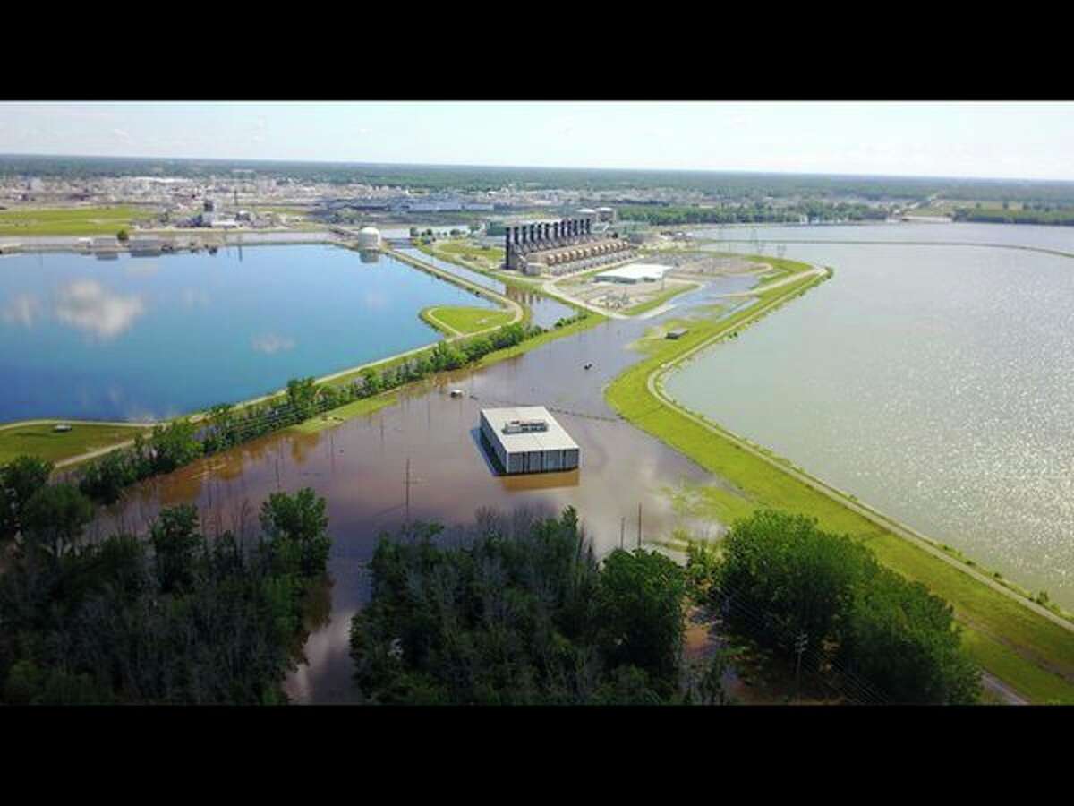 A photo taken by a drone Saturday, submitted by Micah Linton, shows a view between a cooling pond and tertiary pond. Dry land, parking lots and buildings at the center are flanked by floodwater.