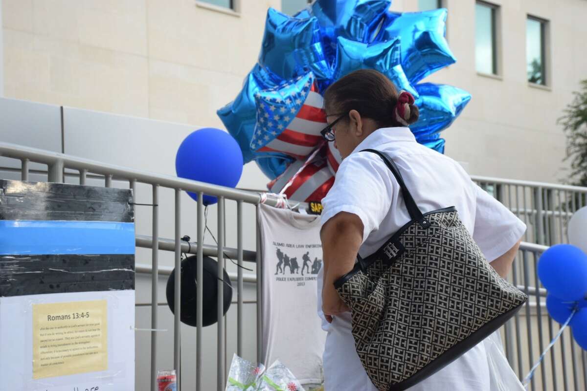 Maria Rubio, an employee at a nearby Bill Miller's BBQ, paused at a memorial for two San Antonio police officers Friday, June 30, 2017. Officer Miguel Moreno, 32, was pronounced dead at 11:11 a.m. Friday at the San Antonio Military Medical Center and Officer Julio Cavazos, 36, who was shot in the chest and is expected to survive