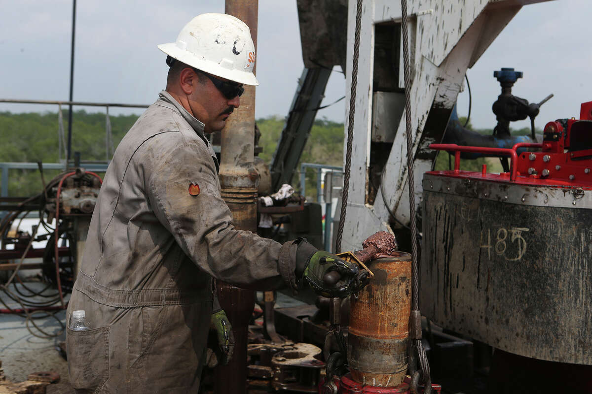 Roughneck Eluid ﻿Cervantes lubricates a section of drilling pipe on an oil drilling rig in Atascosa County, in the Eagle Ford Shale area.
