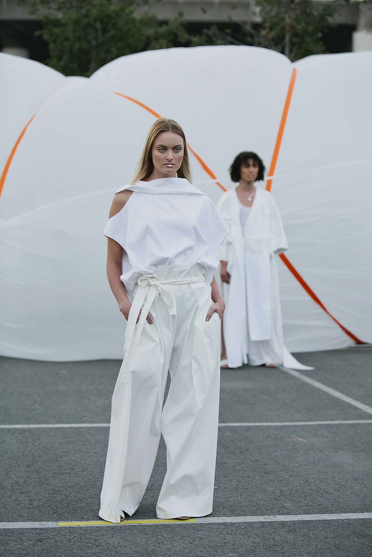 The California College of the Arts show took place on May 11 at the parking lot outside of the school, as groups of models walked among shipping containers and inflated white structures. The main themes were utility, oversize, skydiving and Burning Man-inspired shapes (Camille Malland, Eliza Oakley) and athleisure (Aigne French, Steralda Osias); cuts were relaxed, sleeves long and hems irregular and frayed. Slouchy coats and combat jackets, striking white, pops of neon and of-the-moment cinched �paper bag� pants were recurring items, and sturdy everyday fabrics like fleece, wool and cotton dominated.