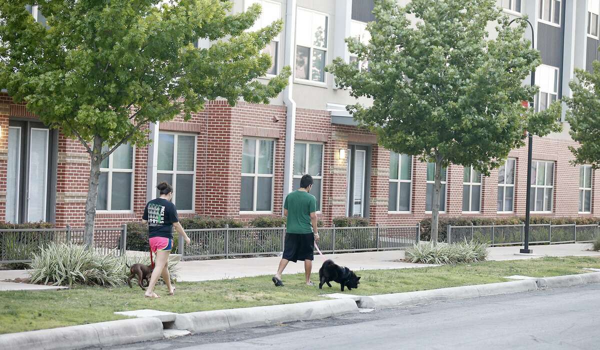 A couple walks their dogs past the area of the officer-involved shooting that occurred Thursday June 29, 2017 near San Antonio College.
