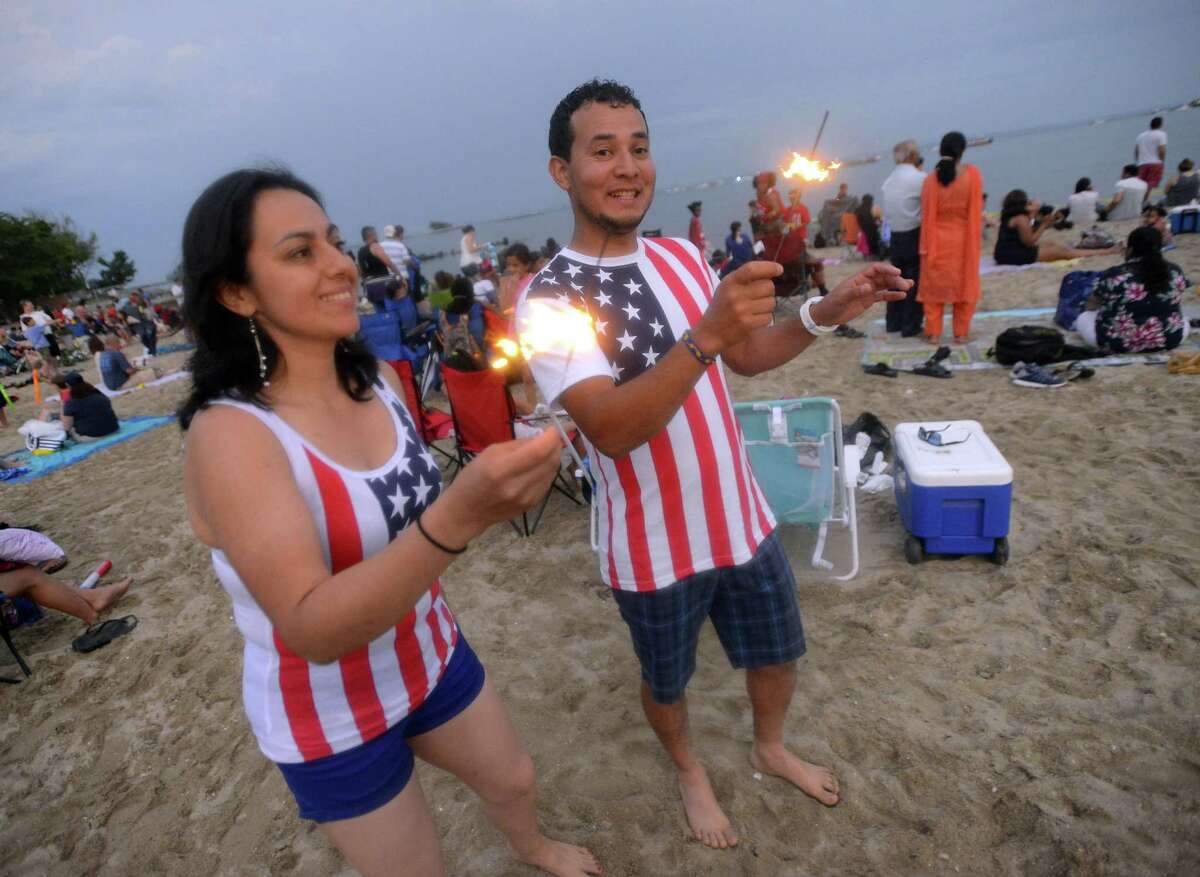 Sondra Ulloa and Oscar Aguero, both of Stamford, dance to music while playing with sparklers prior to a fireworks spectacular lighting up the skies over Cummings Park and Beach on Thursday, June 30, 2017 in Stamford, Connecticut. Several thousand residents weather a passing storm to take in the 20 minute show, enjoying a musical tribute, as they kick off their holiday weekend.