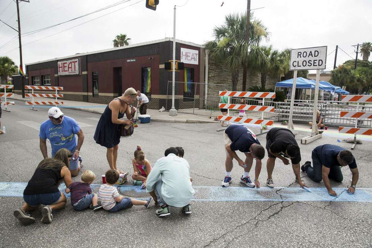 Volunteers use chalk to create a crosswalk in memory of Officer Miguel Moreno, who was shot one block away, at the intersection of Evergreen and Main streets in San Antonio, Texas on July 1, 2017.
