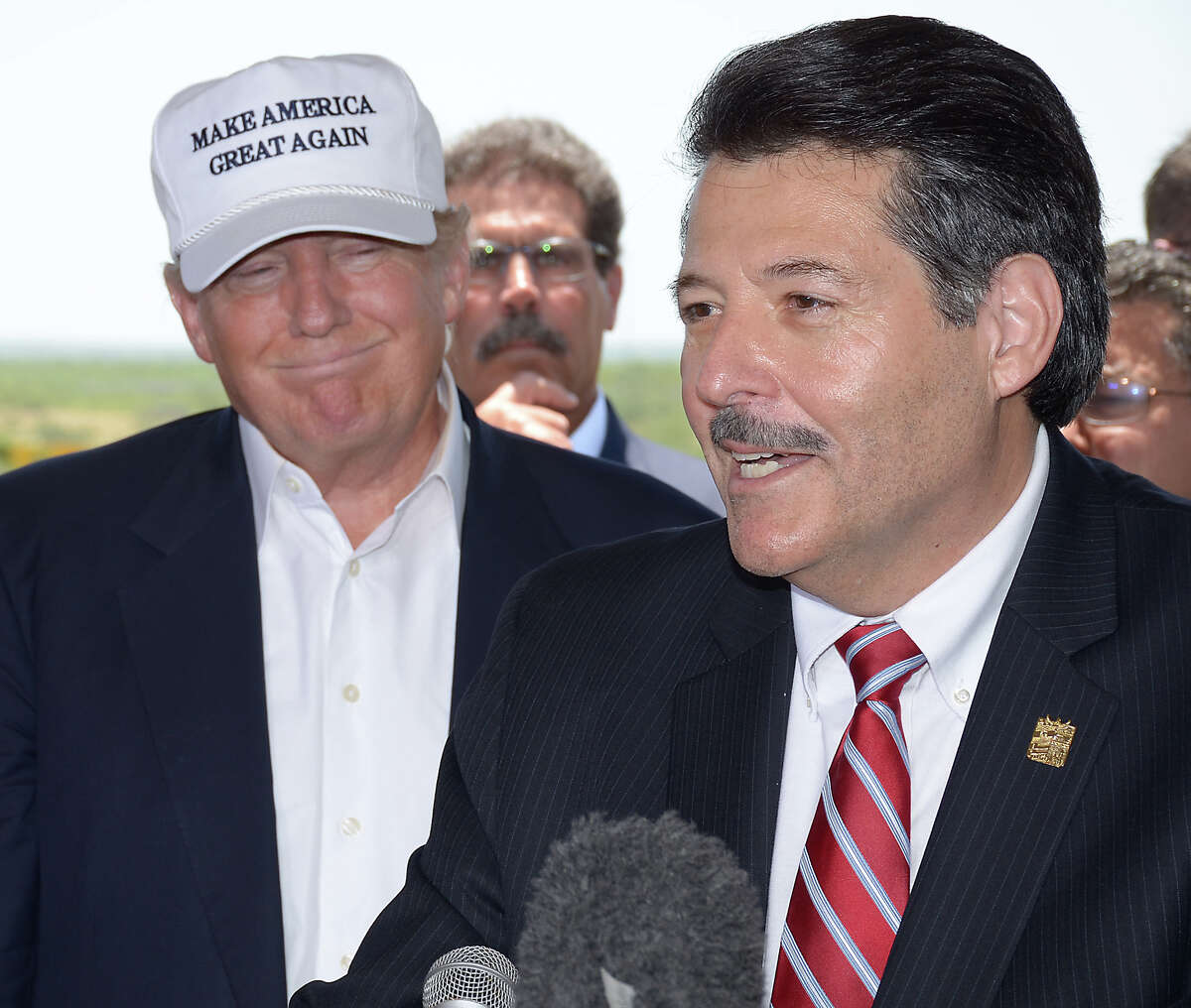 In this file photo, then-Republican Party presidential candidate Donald Trump, left, stands in the background as Laredo Mayor Pete Saenz speaks at a press conference at the World Trade Bridge.