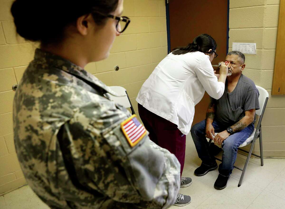 Leonel Presas, right, has his eyes checked Tuesday by Brenda Amaya of the Texas A&M Health Science Center during a traveling clinic at the El Cenizo Community Center in El Cenizo, Texas.