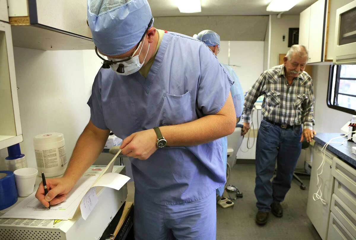 Dr. Mark Judson Burns makes notes Tuesday after fixing a denture for Horacio Gonzalez, 82, in a mobile dental clinic in the El Cenizo Community Center.