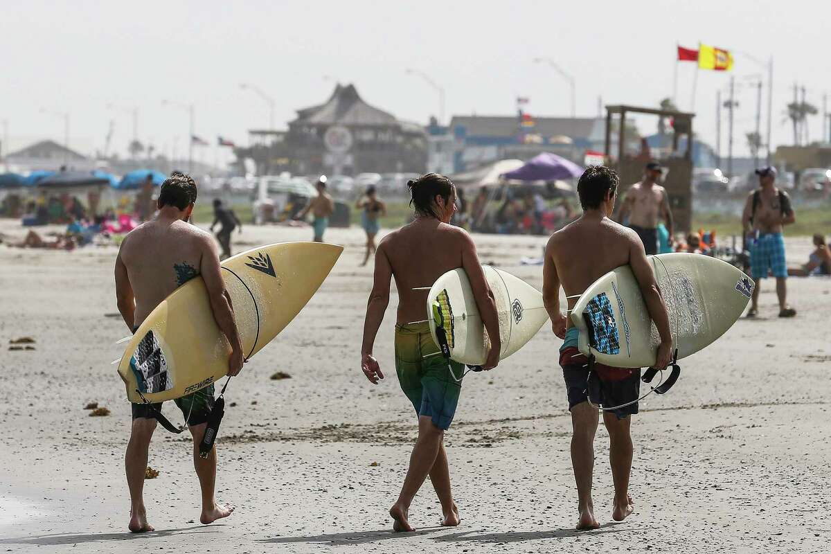 Surfers walk out of the surf as people enjoy the beach over the long holiday weekend Saturday, July 1, 2017 in Galveston. ( Michael Ciaglo / Houston Chronicle )