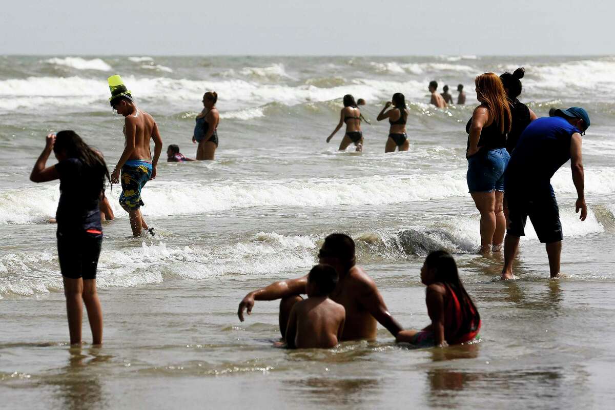 A boy walks into the ocean with a bucket on his head as people enjoy the beach over the long holiday weekend Saturday, July 1, 2017 in Galveston. ( Michael Ciaglo / Houston Chronicle )