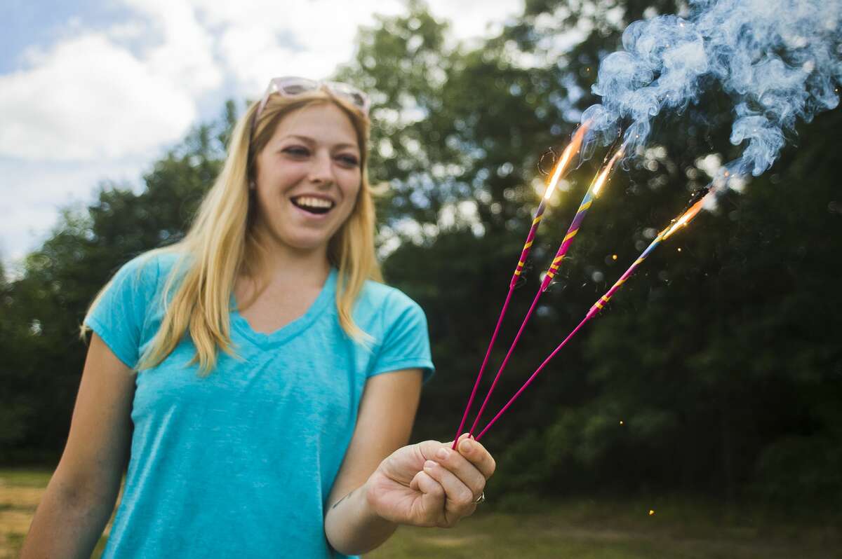 Amber Swisher of Alma tests a package of sparklers next to a fireworks tent at the intersection of Eastman and Wackerly on Monday, July 3, 2017.
