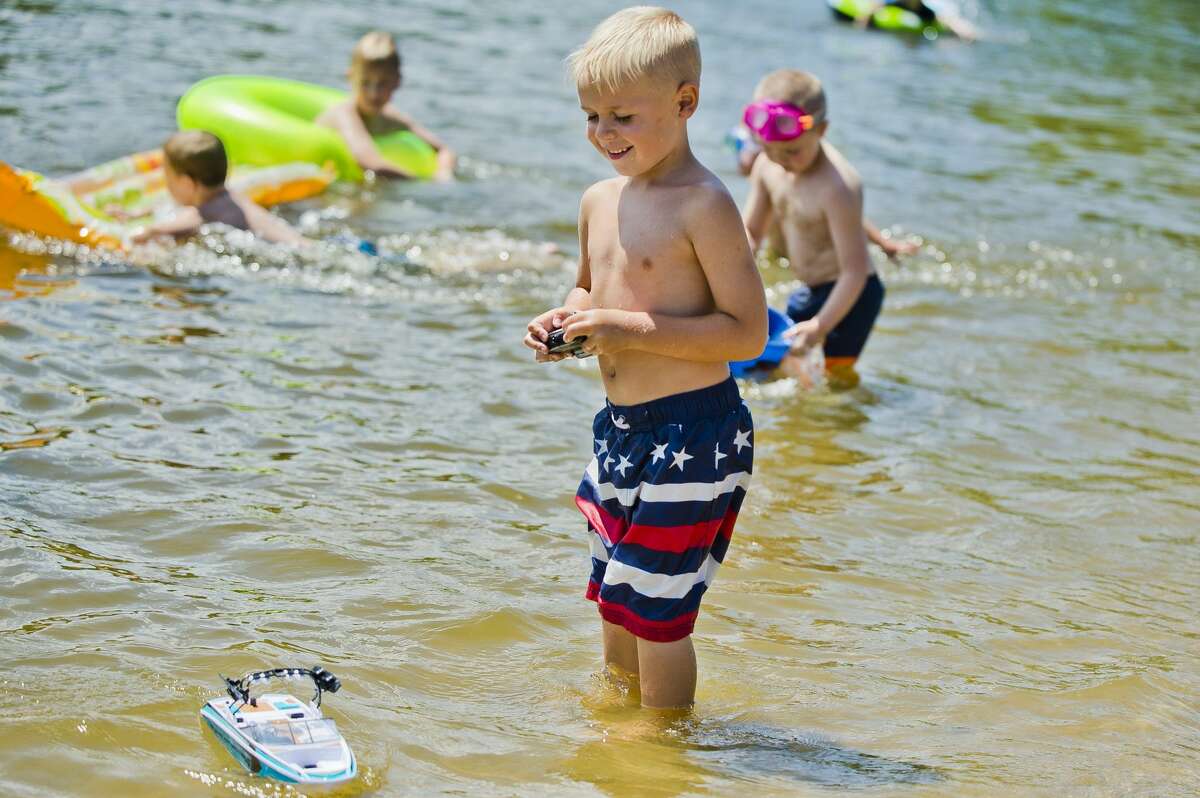 Mason Stewart, 5, of Bay City, plays with a remote controlled boat, a gift from his grandmother, as they enjoy a sunny Independence Day at Stratford Woods Park on Tuesday, July 4, 2017 in Midland.