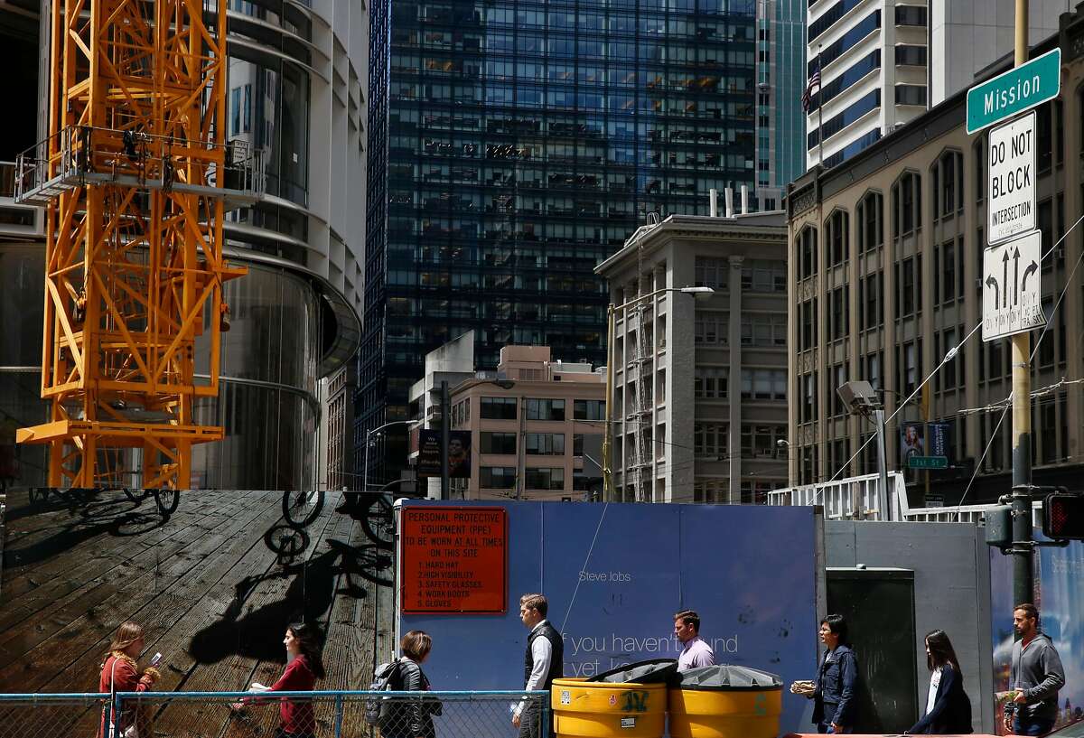 Pedestrians walk past the future spot of a plaza at the base of the new Salesforce Tower on the corner of Mission and Fremont streets July 5, 2017 in San Francisco, Calif.