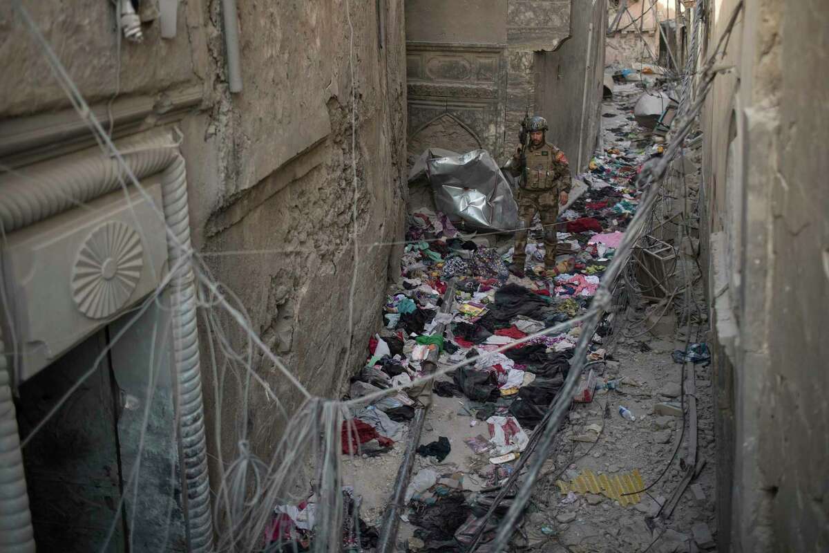 An Iraqi soldier walks on clothes left behind by fleeing civilians in an alley as Iraqi forces continue their advance against Islamic State militants in Mosul.