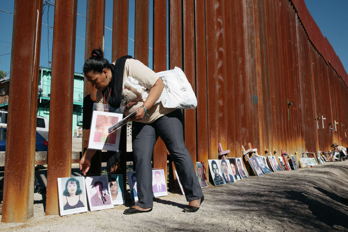Nohemy ﻿Alvares spreads ﻿photographs of disappeared family members against the wall along the Mexico and Arizona border ﻿in Nogales, Sonora, Mexico. Her son, Gilver, is among the missing. "He had dreams of owning a car and house."