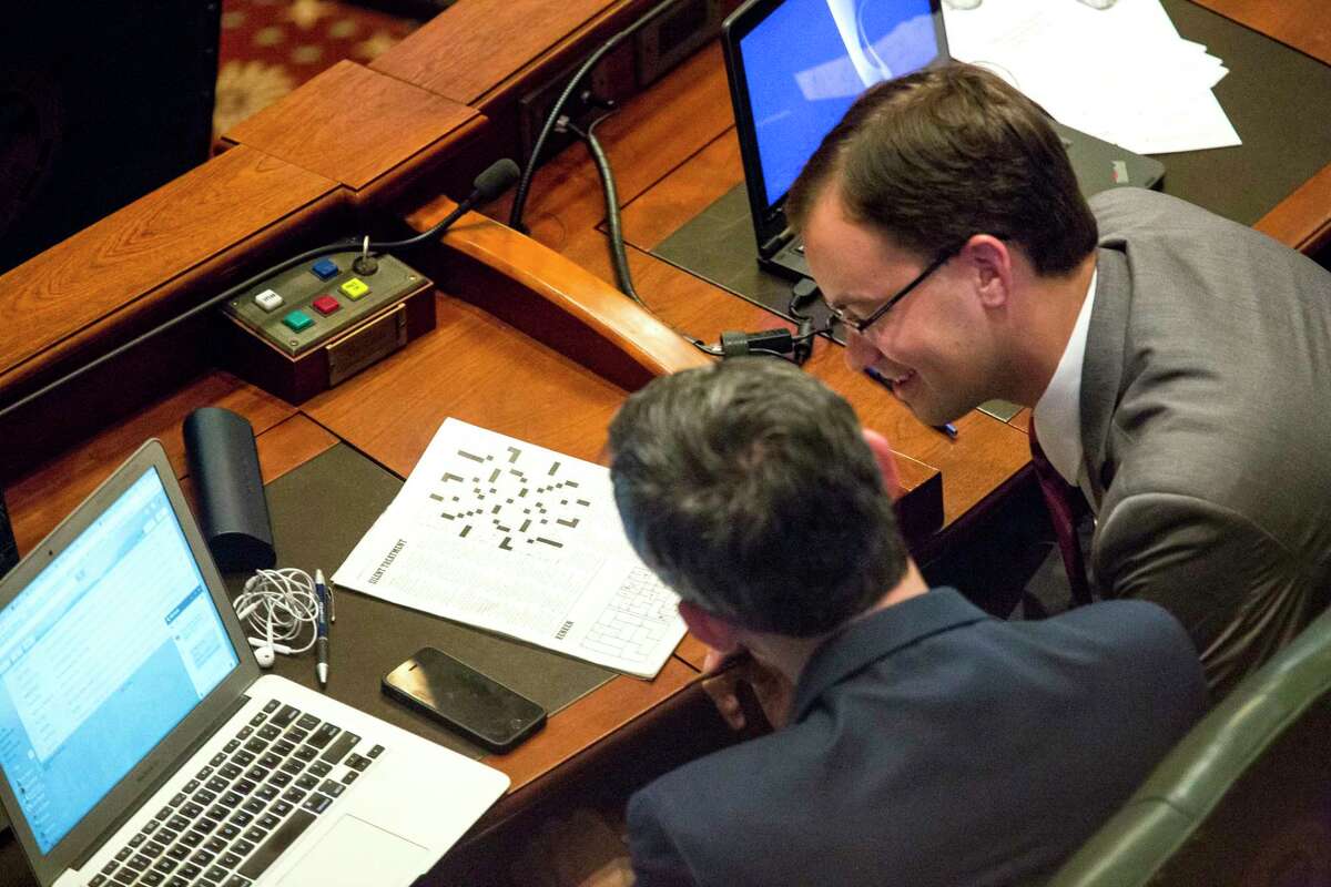 Rep. Will Guzzardi, D-Chicago, left, and Rep. David Olsen, R-Downers Grove, work on a puzzle on the House floor while the state Capitol is on lockdown during a hazardous materials incident Thursday, July 6, 2017 in Springfield, Ill. A financial showdown more than two years in the making was slated to play out in the Illinois House on Thursday as Democrats try to enact a $36 billion spending plan fueled by a 32 percent income tax increase over the Republican governor's objection. (Rich Saal/The State Journal-Register via AP)